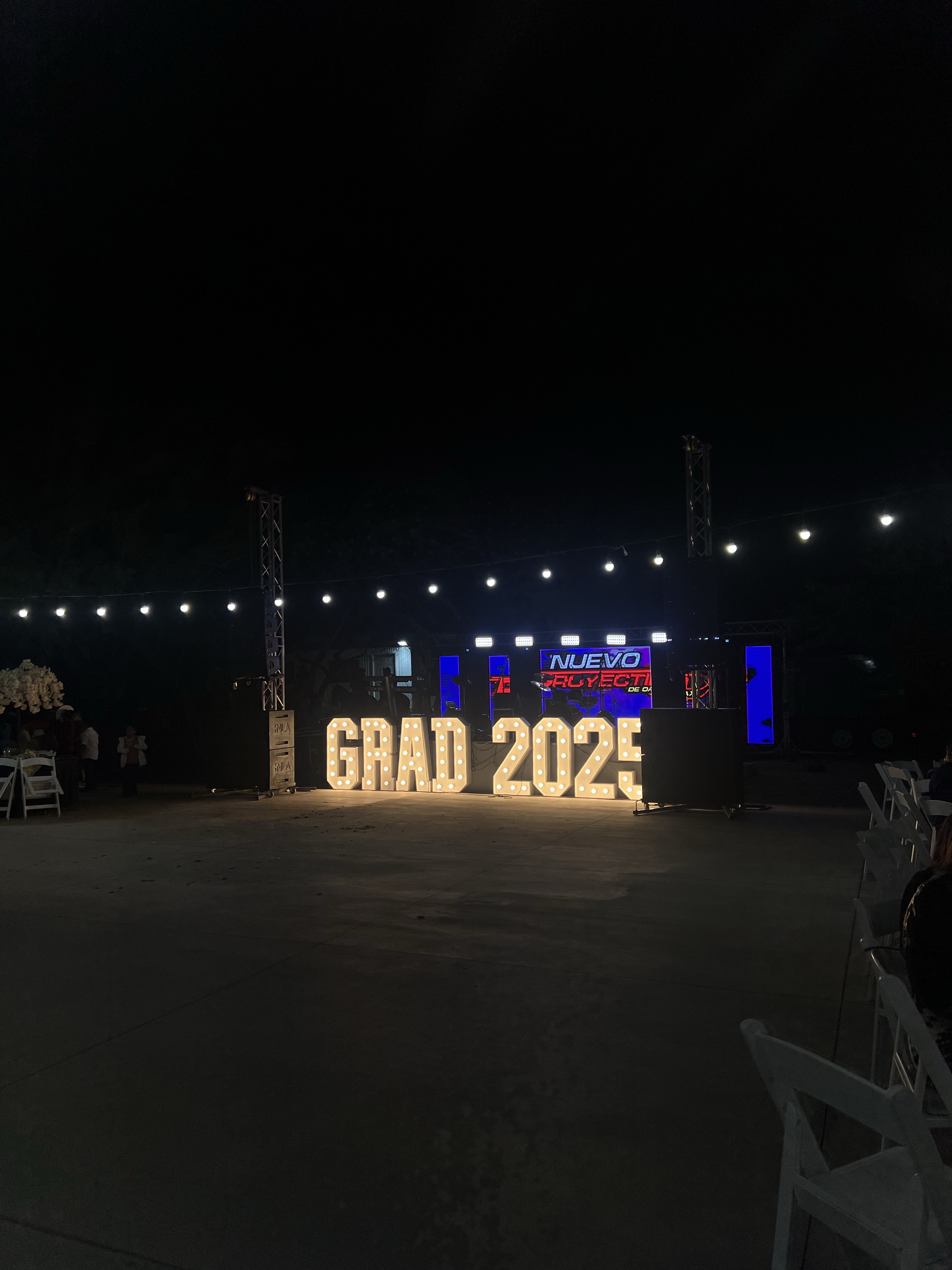 Light-up marquee letters spelling GRAD 2025 at a nighttime graduation event